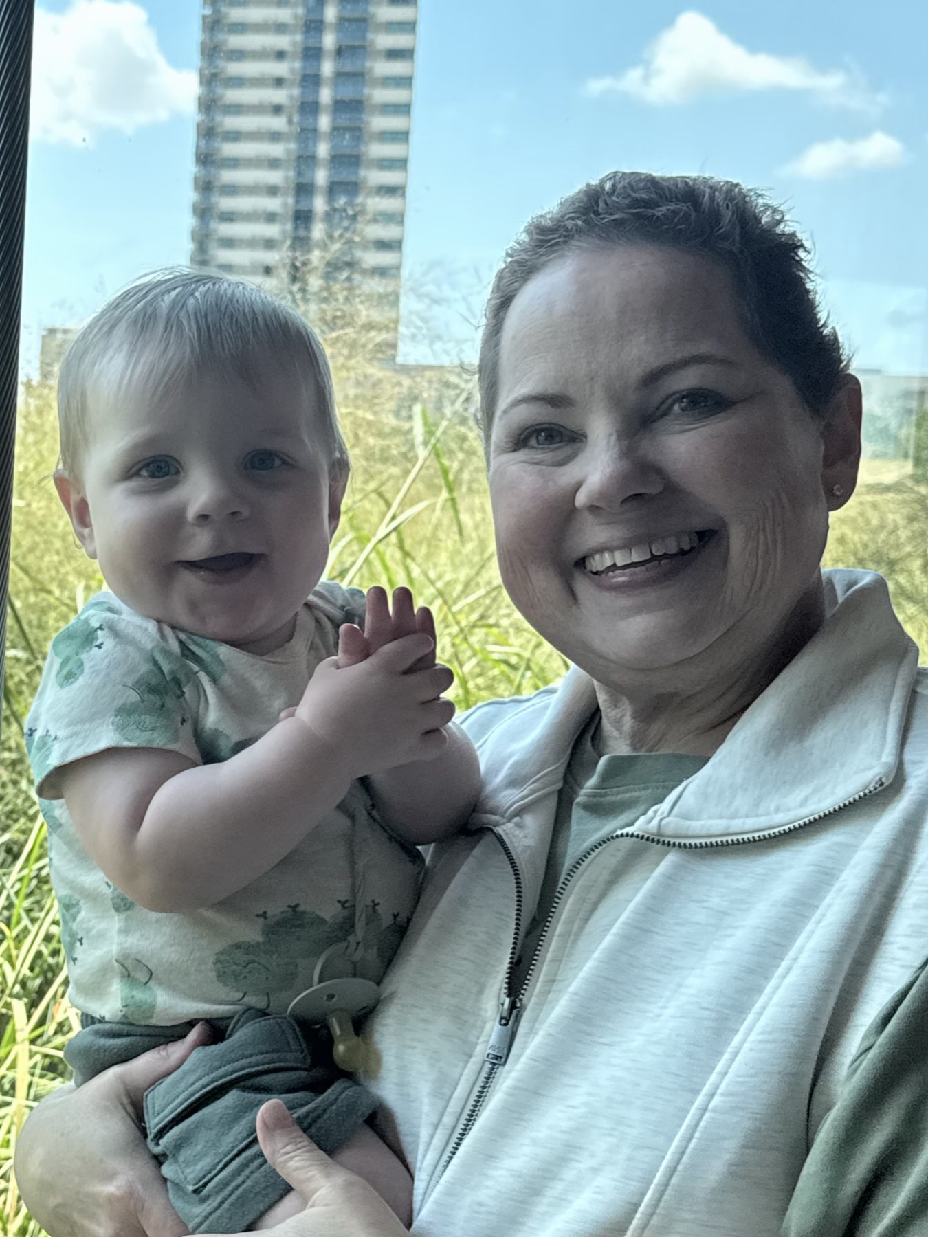 Amy holding her grandson outdoors on a sunny afternoon.
