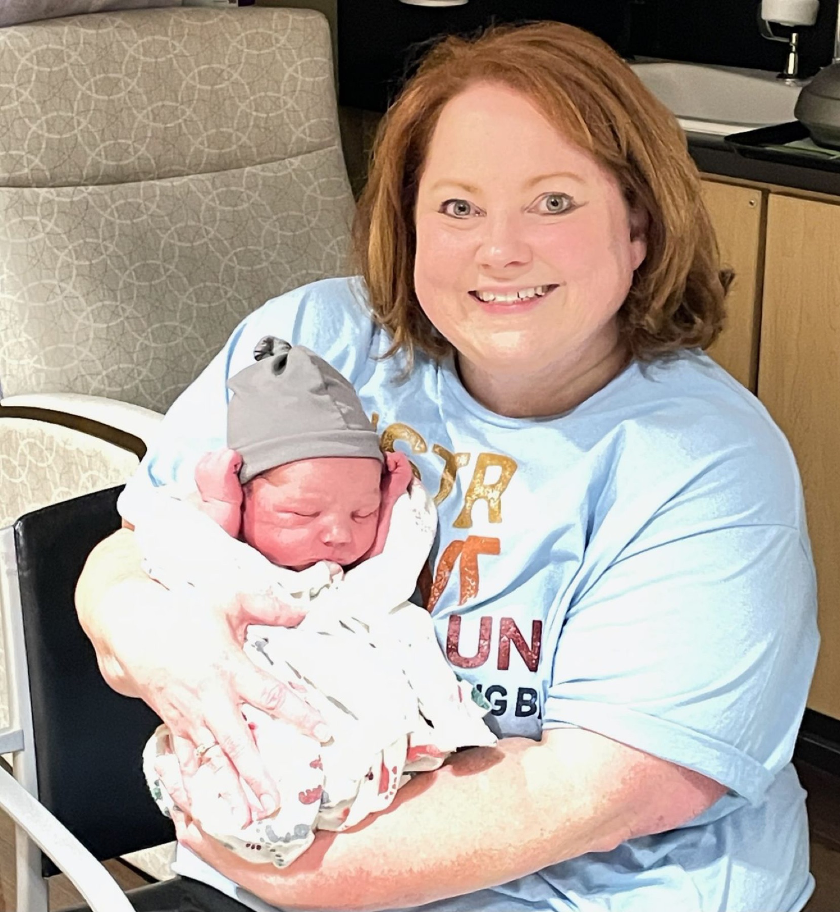 Amy cradling a sleeping newborn in the family.