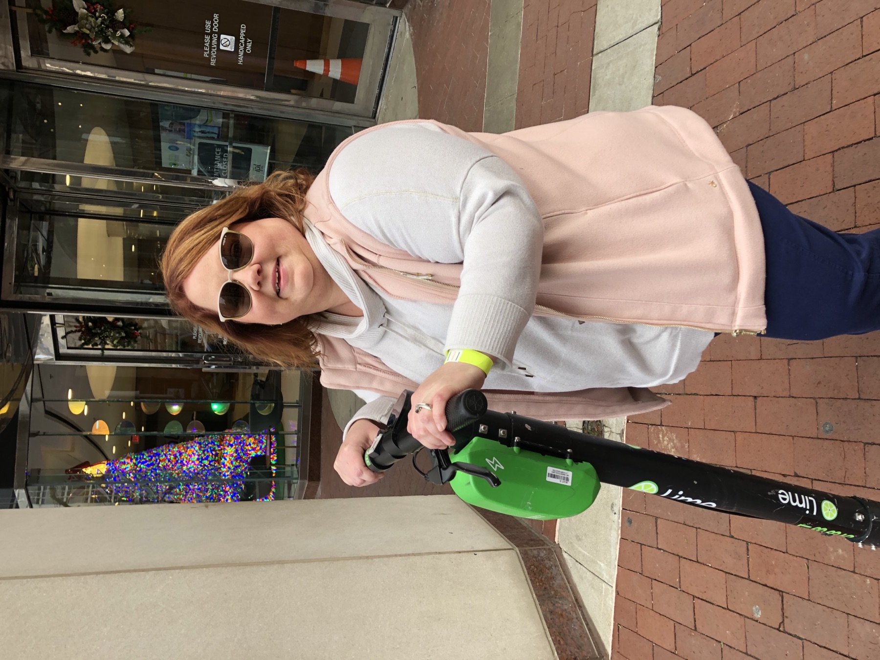 Amy riding a green Lime scooter through downtown.