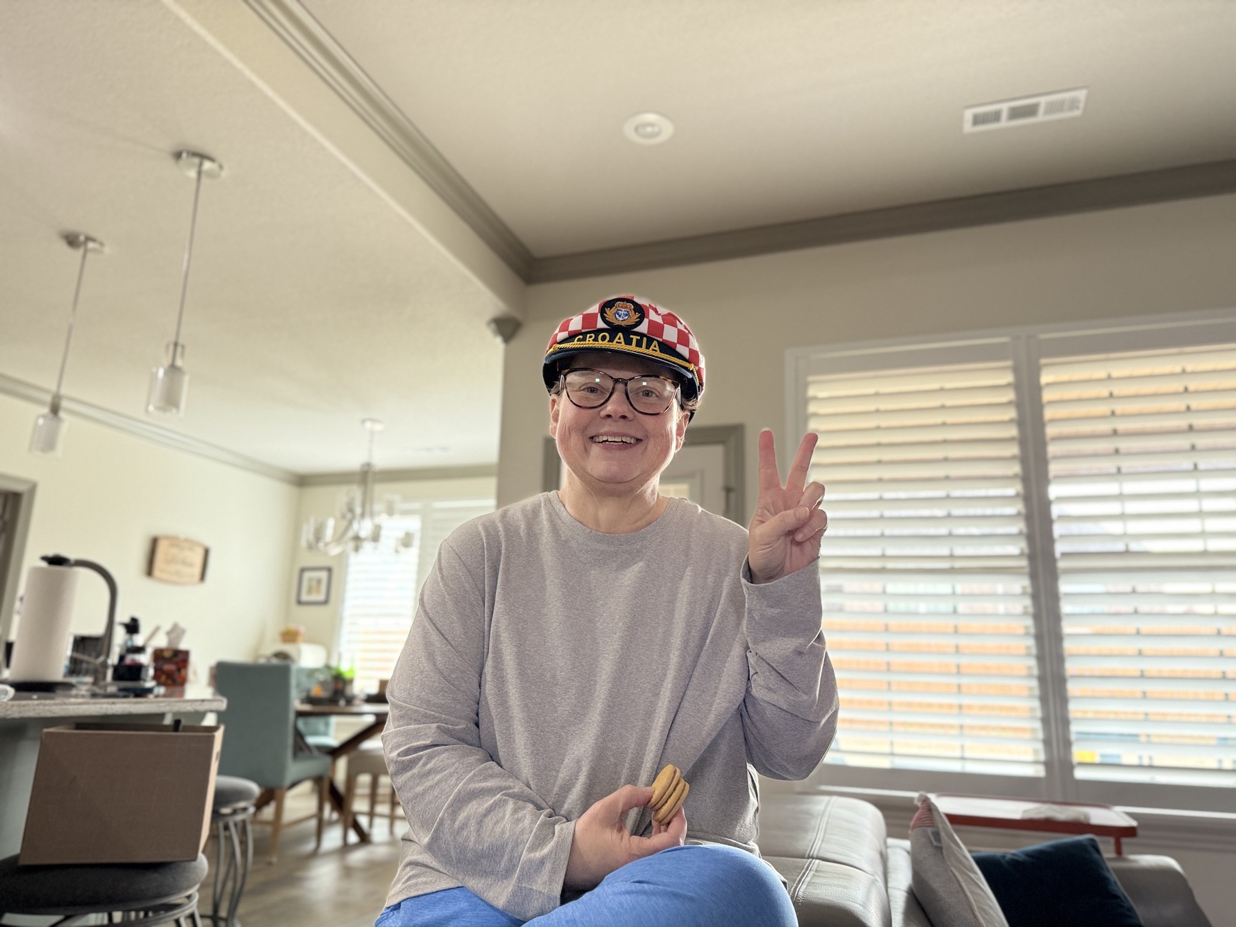 Amy flashing a peace sign in a Croatia captain's hat at home.