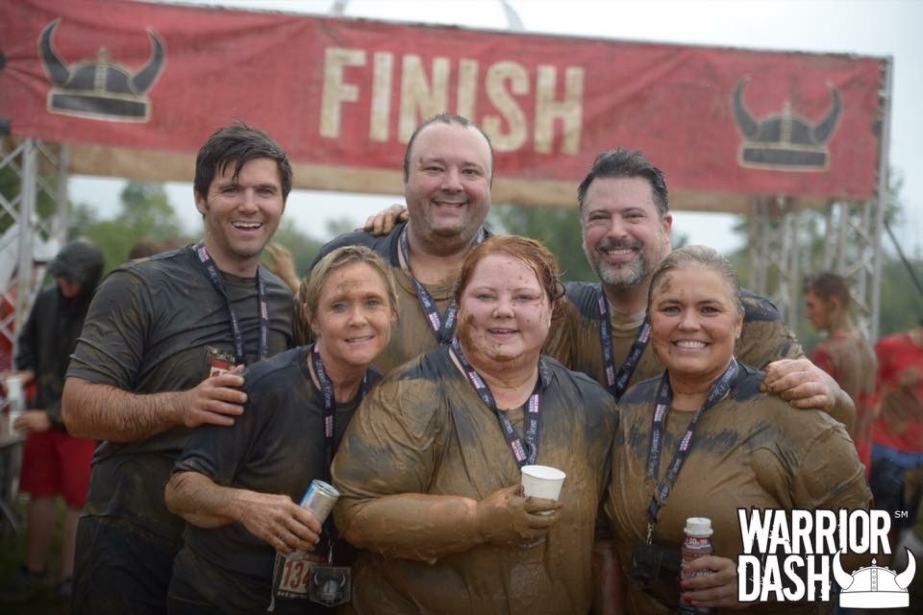Amy with friends and family at the Warrior Dash finish line, covered in mud and smiles.
