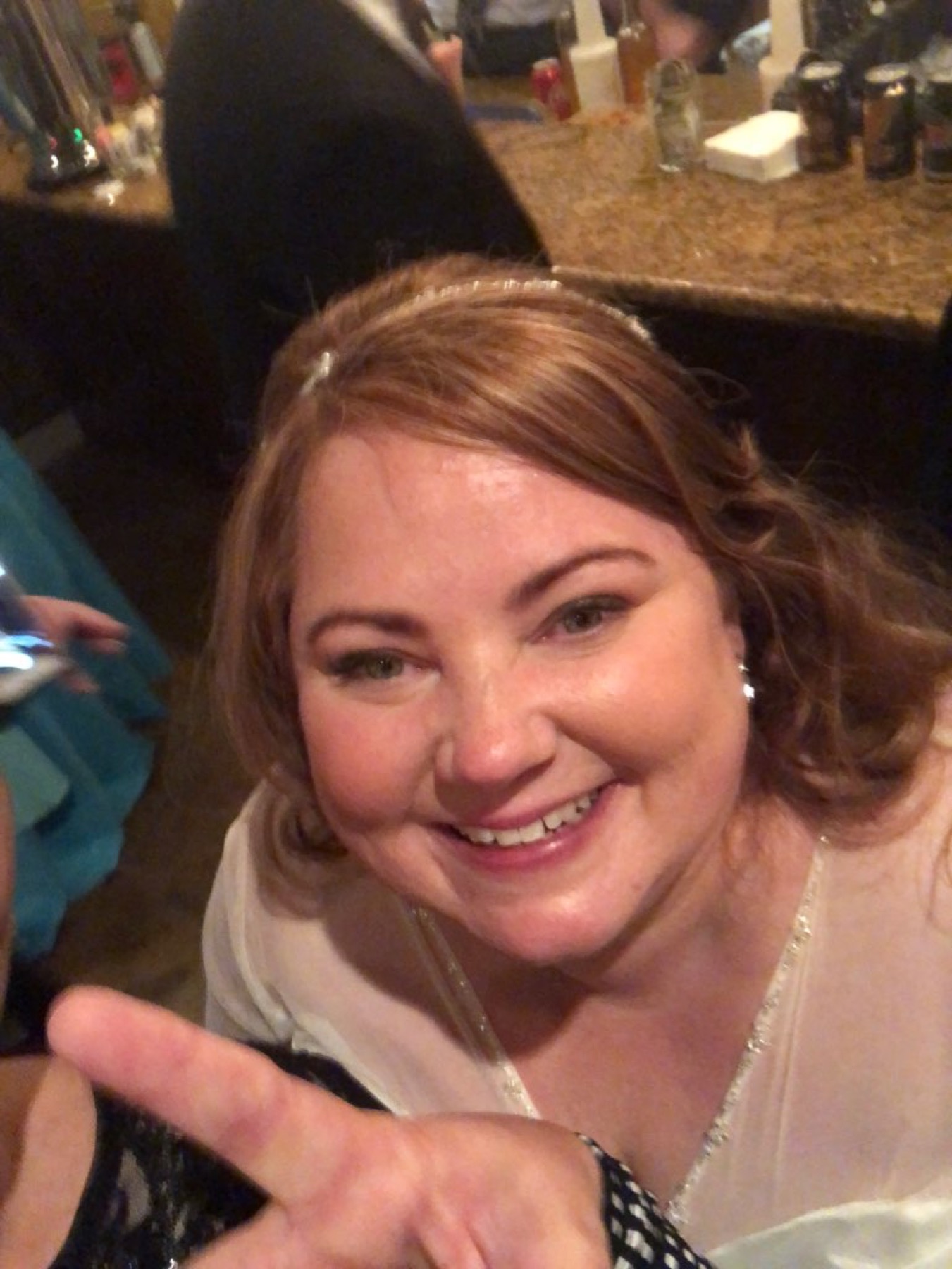 Amy dressed up for a celebration, smiling and giving a peace sign.